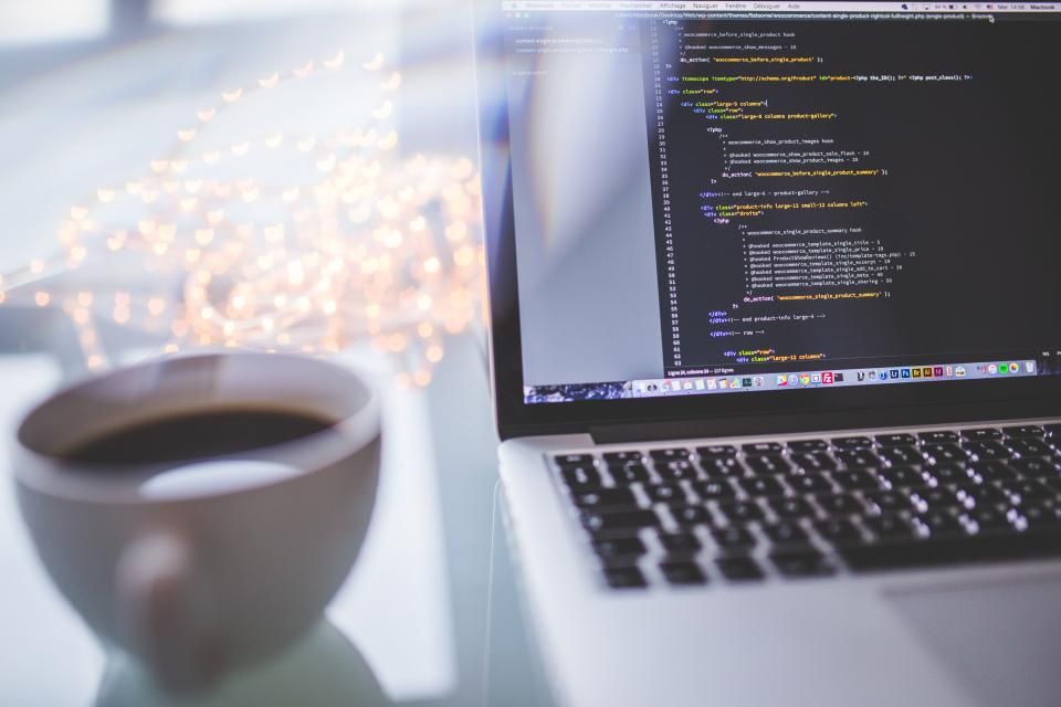 Ordinateur portable affichant du code d’automatisation à côté d’une tasse de café