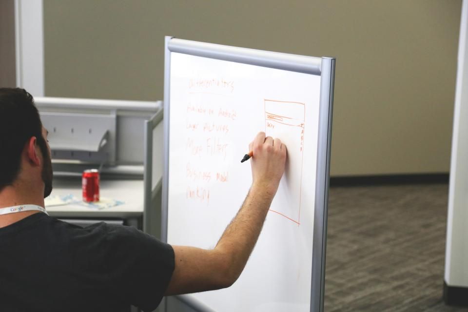 Personne présentant un plan de produit sur un tableau de conférence