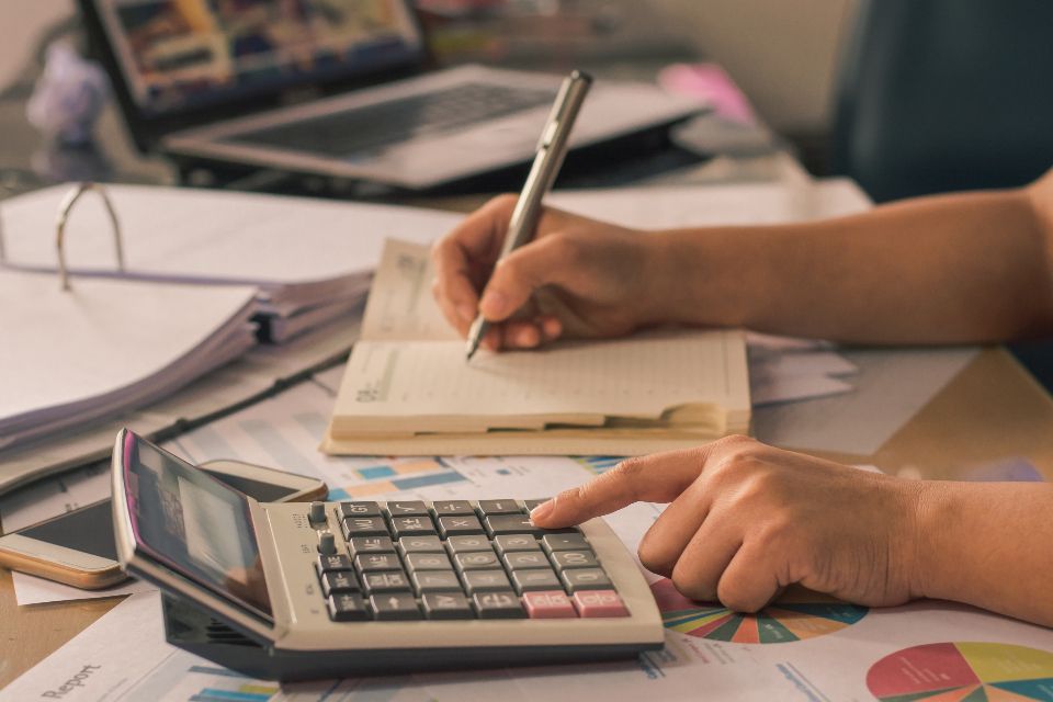 Personne remplissant un document comptable avec une calculatrice